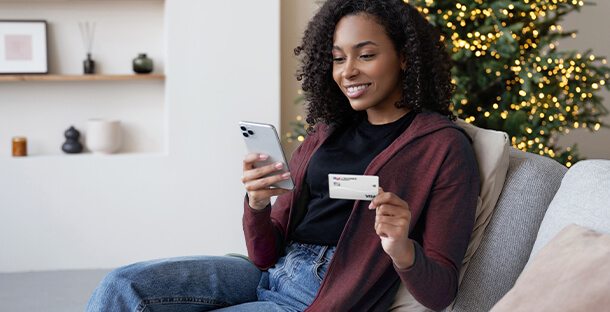 A woman uses her USALLIANCE credit card to make a purchase on her phone.